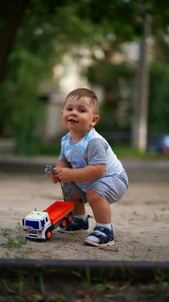 Портрет Милий Маленький Хлопчик Присідає Біля Іграшкової Машини Посміхається Відкритому — стокове фото