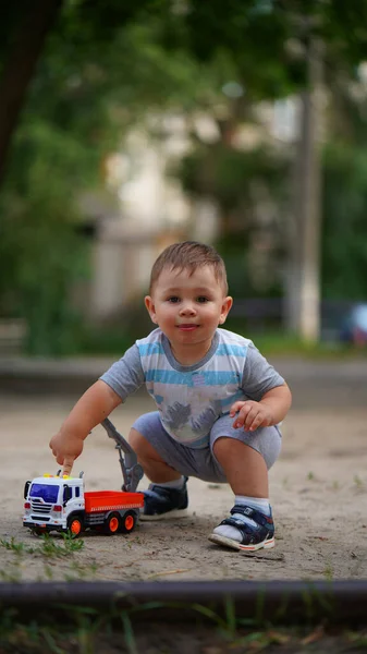 Портрет Милий Маленький Хлопчик Присідає Біля Іграшкової Машини Посміхається Відкритому — стокове фото