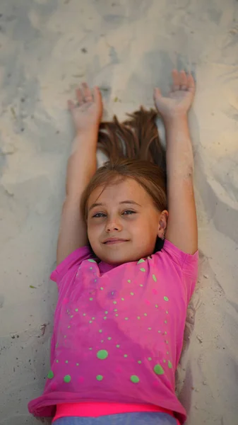 一个美丽的小女孩躺在沙滩上 胳膊张开的画像 — 图库照片