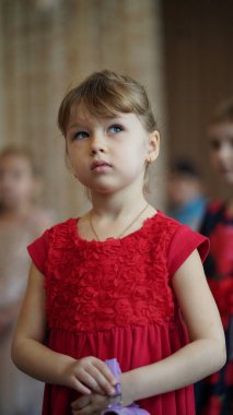Anaokulundaki festivalde çocuk performansı. Güzel kırmızı elbiseli, dans eden güzel kızlar.