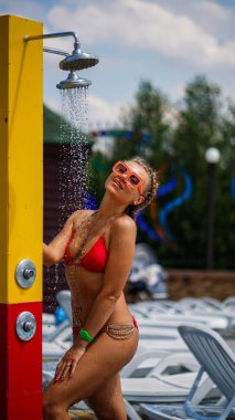 Saçları örgülü güzel bir kadın su parkında akan suyun altında duruyor..