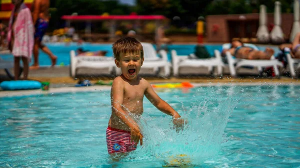 小さなかわいい男の子膝立って 澄んだ水の公園でボールを投げるの深さ 泣いたり喜びを示したり — ストック写真