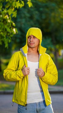 Yüzünde sakalı olan, sarı ceketli, genç, gülümseyen bir sporcu.