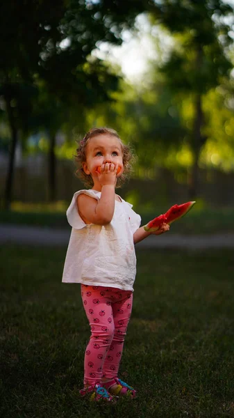 Malé Blonďaté Dítě Bílé Košili Stojící Tmavém Parku Kusem Melounu — Stock fotografie