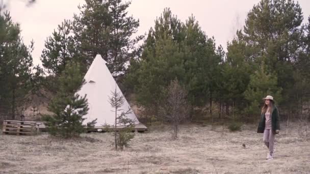 Ung trevlig kvinna gå genom landsbygden till glamping utanför teepee. Långsamma rörelser — Stockvideo