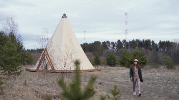 Young beautiful woman walking through countryside to glamping outside teepee. Slow motion — Stock Video