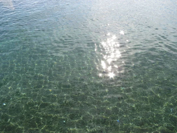 Fondo ondulado de agua azul, tirquise con reflejo de destello solar. mar, océano, piscina. Concepto de relax, calma, vacaciones tropicales . — Foto de Stock