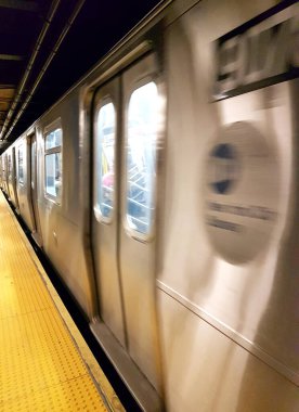 New York metro istasyonunda tren hızlanıyor. Varmak ya da gitmek. Hareket bulanıklığı etkisi.