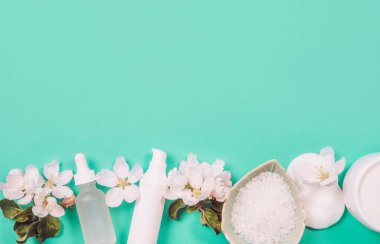 Temiz, saf bahar güzellik ürünleri arka planında fotokopi alanı, ortasında yazı için yer var. Beyaz nesneler, nane yeşili arka plan, süs için beyaz taze elma ağacı çiçekleri..