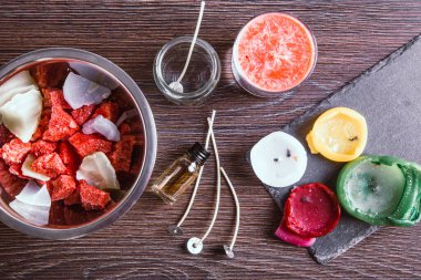 Eski mumları yeniden kullanmak ve eritmek için kullanılan aletlerin düzlüğü: masadaki çeşitli malzemeler: mum fitilleri, cam kavanoz, eski mumlar, aroma yağı yağı. 