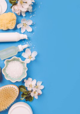Genetik temiz bahar güzellik ürünleri arka planında fotokopi alanı, ortasında yazı için yer var. Beyaz kaplar, mavi arka plan, süsleme için beyaz elma ağacı çiçekleri..