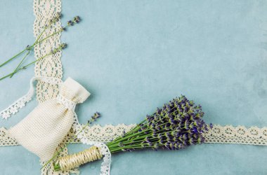 Üst manzara mavi desenli arka plan. Etrafı taze lavanta dalları ve pamuklu dantelli kokulu lavanta torbalarıyla çevrili. Romantik klasik arka plan konsepti.