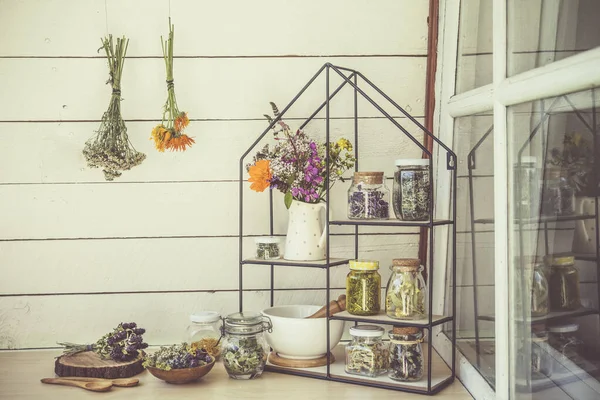 收集各种药用植物 在玻璃瓶中烘干 并在墙上烘干 现代架子上的瓷壶里有罐子 沙砾和草本野花花束 复古风格的老式过滤器 — 图库照片