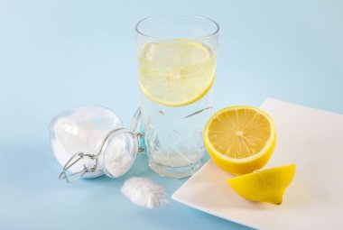Su ve limon dilimli içecek bardağında kabartma tozu sindirim sistemi konsepti için sağlık faydaları. Açık mavi arkaplan.