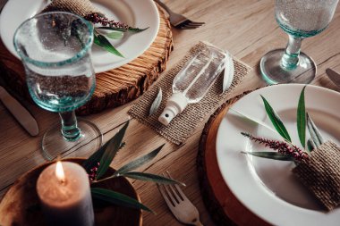 Restoran masasının ortasında el dezenfektanı şişesi var. Yaprak ve çiçek desenli beyaz tabaklar. Virüs önleme yayıyor, yeni gerçeklik. 