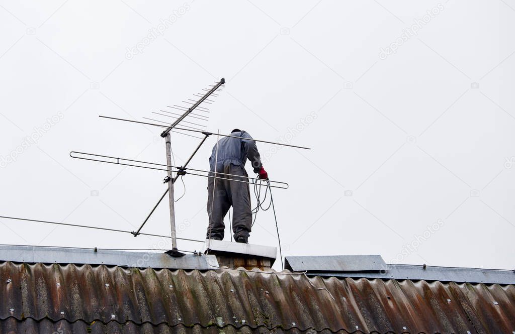 Chimney sweeper clears ash and soot from chimneys on cloudy autumn day. 