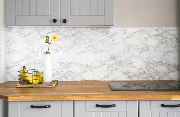 Modern, gri renkli, kendine yapıştırıcı sahte mermer taklit bantlı mutfak. Küçük sobanın içine inşa edilmiş saf, doğal ahşap tezgah..