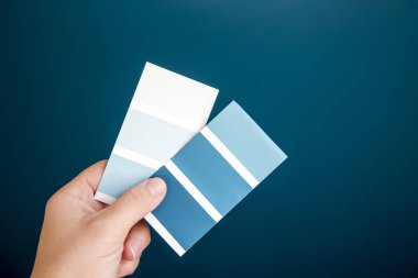 Farklı mavi renkte el ele tutuşan ve ev boyası seçen birinin yakın görüntüsü. Ev geliştirme kavramı.