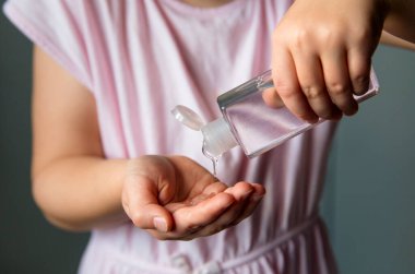 Ellerinde küçük taşınabilir antibakteriyel el dezenfektanı kullanan 6 yaşındaki bir çocuğun görüntüsünü kapat..