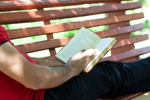 Genç adam sokakta kitap okuyor.