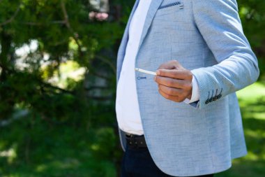 Adam sokakta sigara içiyor.