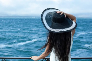 Denizde şapka tutan kadın.