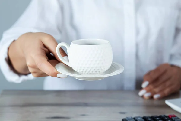 woman hand cup of coffee with document on desk