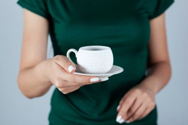 Bir fincan kahve ya da çay tutan bir kadın. 