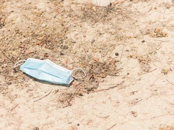 a face mask lying on the ground on a sunny day