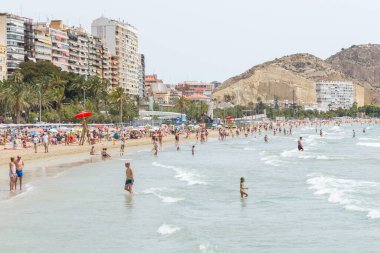 Alicante, İspanya; 08 Temmuz 2020; güneşli bir yaz gününde güneşlenen ve yüzen insanlarla dolu Postiguet plajı