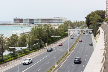Alicante, İspanya; 8 Temmuz 2020; güneşli bir yaz gününde, arka planda binalar ve açık gökyüzü olan el postiguet plajının yanındaki araba dolu yol.