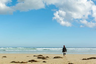 Sahilde sırtüstü yürüyen bir kadın.