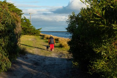 Yaşlı kadın köpeğini gezdiriyor.