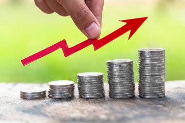 Aşağıdan yukarıya sıralanmış bozuk paraların üzerindeki kırmızı oklar. İş büyümesi konsepti Emlak Finansal Planlama Hesap Yönetimi ve bir başarı grafiği.