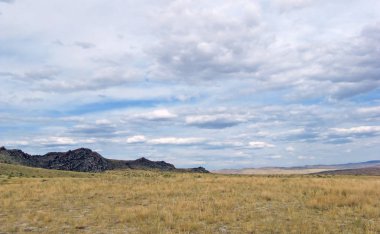 Beyaz bulutlar Sayan Dağları Sibirya Rusya ile mavi gökyüzü altında sarı çim ile geniş bozkır