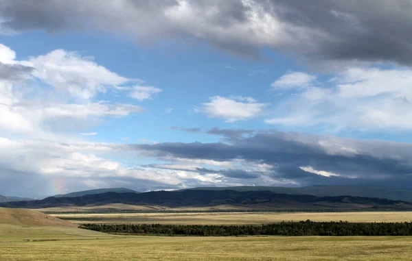 Estepa larga com grama amarela sob um céu azul com nuvens brancas Montanhas Sayan Sibéria Rússia — Fotografia de Stock