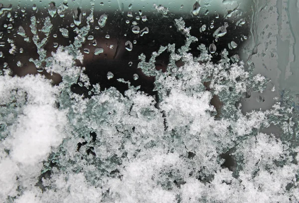 Λιώνουν το χιόνι πάνω στο γυαλί. χιονόνερο σε γυαλί — Φωτογραφία Αρχείου