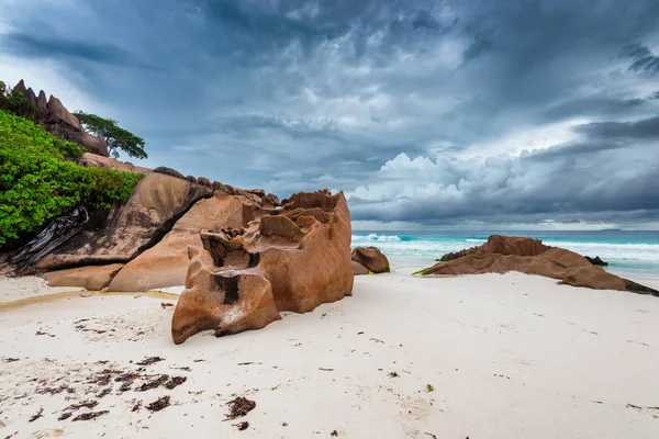 Dramatic stormy sky and shaped granite boulders in the beach of Seychelles at Anse Source d\'Argent beach at stormy day. Island of La Digue, Seychelles.