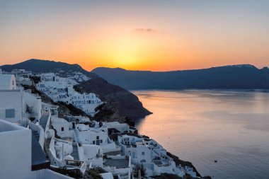 Santorini gün doğumu. Yunanistan 'ın Santorini adasındaki Oia köyündeki geleneksel beyaz evlerin inanılmaz günbatımı manzarası.