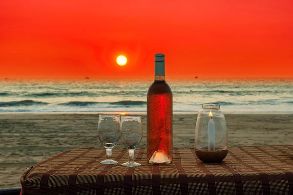 Sunset at beach cafe with rose wine and umbrella on a tropical beach in GOA, India