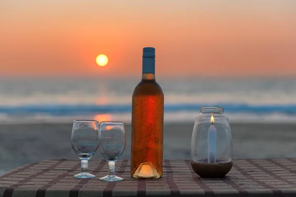 Sunset at beach cafe with rose wine and wine glasses in beach party on a tropical beach in GOA, India