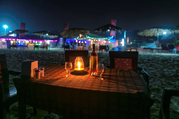 Beach party at night in beach cafe with bottle of rose wine and glasses on the table , GOA, India..