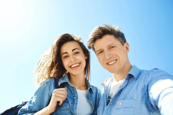 Onnellinen hymyilevä pari, houkutteleva mies ja nainen katselee kameraan taivaalla taustalla . — kuvapankkivalokuva