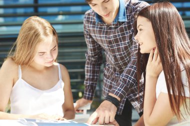 Üç mutlu lise öğrencisinin portresi. Öğrenci arkadaşlar öğrenir, ödevlerini birlikte yapar, zaman geçirir ve eğlenirler. Adam kızlara bir şey anlatıyor ve defterinde yazıyor.