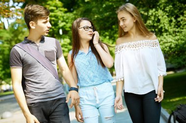 Üç mutlu arkadaş öğrenci birlikte parkta mükemmel bir şekilde vakit geçiriyorlar.