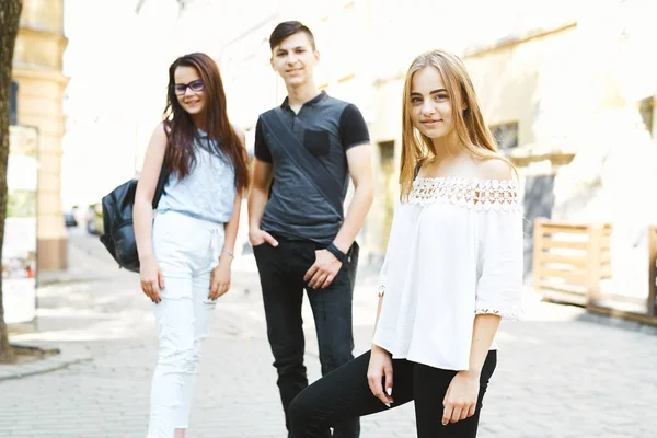 3人の幸せな友人学生が一緒に街を散歩します 友達が一緒にポーズをとってカメラを見ると ブロンドの女の子に焦点を当て — ストック写真