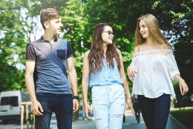 Üç mutlu arkadaş öğrenci parkta yürürken birlikte mükemmel zaman geçiriyorlar. Arkadaşlar bir şeyleri tartışırken eğleniyorlar.