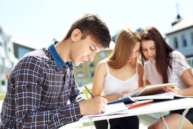 Üç lise öğrencisi. Öğrenci arkadaşlar öğrenir, ödevlerini birlikte yapar, dışarıda vakit geçirirler. Ön plandaki öğrenci.