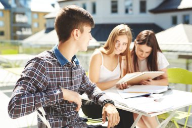 Üç lise öğrencisi. Öğrenci arkadaşlar öğrenir, ödevlerini birlikte yapar, dışarıda vakit geçirirler. Ön plandaki öğrenci.