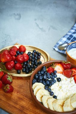 kase çilek, muz ve ekşi krema, taze meyveler ve yazlık Kahvaltı, yatay süzme peynir. karanlık beton zemin üzerinde bir yemek Gıda ile üstten görünüm